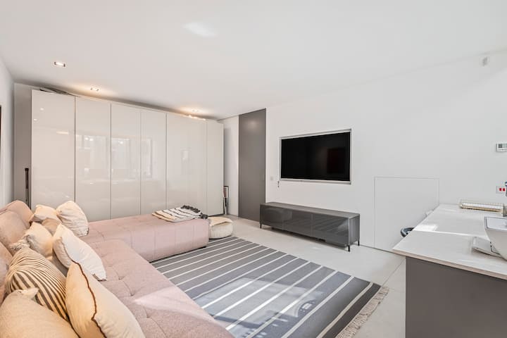 时尚现代的媒体室，配有舒适的组合式座椅、壁挂式电视和光亮的嵌入式衣柜。柔和的中性色调、简洁的线条和微妙的灯光营造出平静、精致的空间，是放松身心或在城市中度过一天后舒缓压力的理想场所。