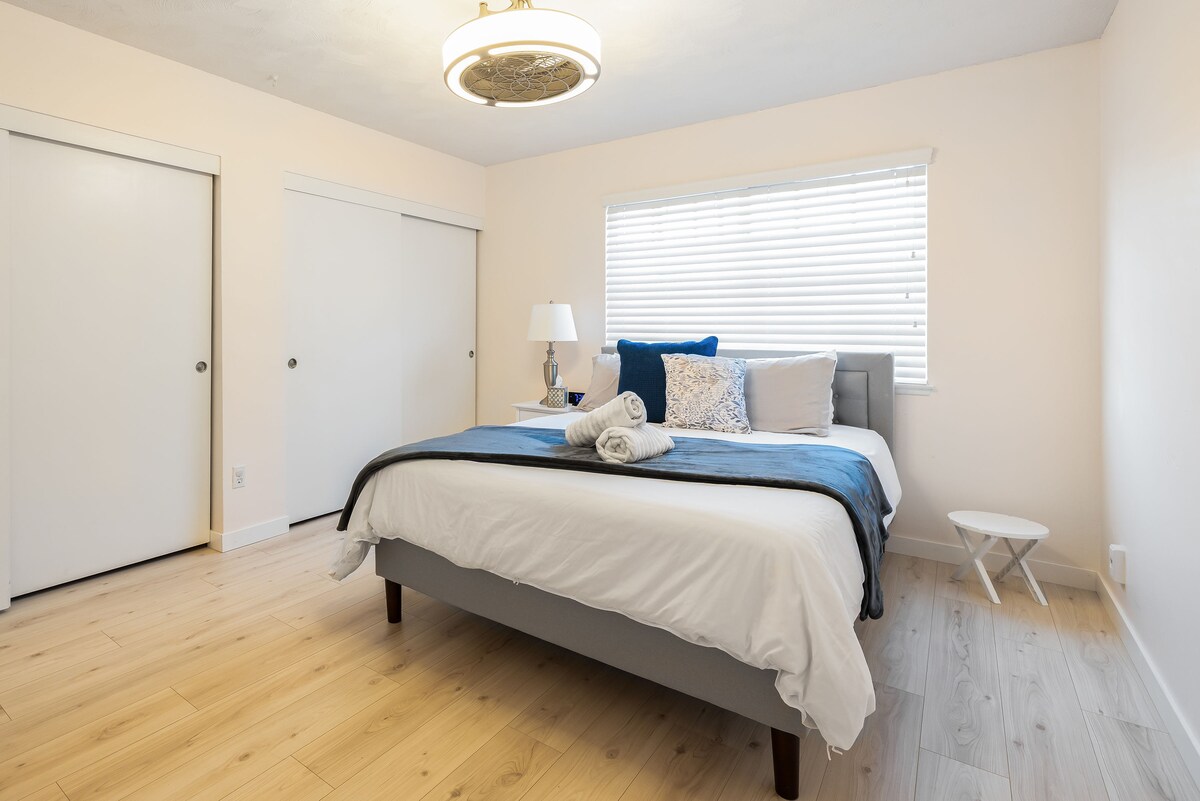 Mekani bračni krevet sa stilskim sivim uzglavljem, ukrašen svježom bijelom posteljinom i umirujućim plavim prekrivačem, osigurava miran san. 