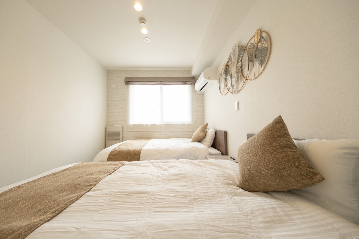 هذه غرفة نوم بها سريران شبه مزدوجين مع مراتب سيمونز