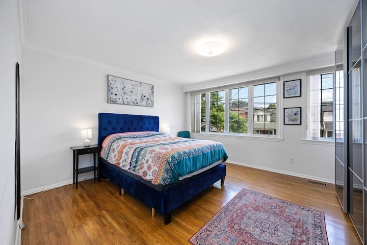 Godoro la ukubwa wa kifalme katika chumba cha kulala chenye nafasi kubwa na mwanga mwingi wa asili. 