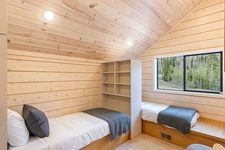 الطابق الثاني مع سريرين مفردين مع أسقف عالية وخزائن. 