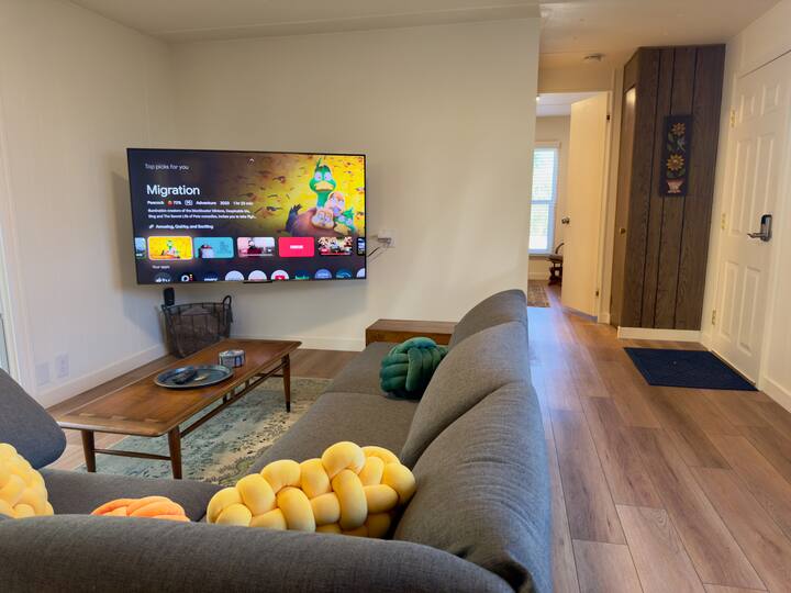 โซฟาแบบ Burrow Range พร้อมทีวี UHD ขนาด 65” บนที่ติดผนังแบบสวิงได้เต็มที่