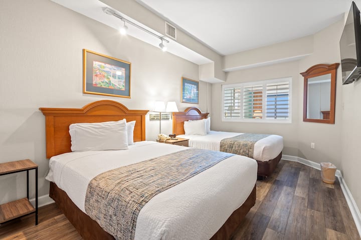 Priestranná spálňa s dvoma plyšovými manželskými posteľami s čerstvou posteľnou bielizňou v hotelovom štýle. Veľká nástenná inteligentná televízia smeruje k lôžkam, zatiaľ čo veľké zrkadlo, priestranný šatník a komoda poskytujú dostatok úložného priestoru a vytvárajú atmosféru čistého a oddychového útočiska.