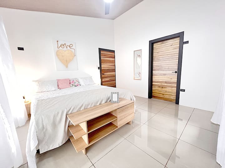 Amplia habitación con baño en suite de diseño moderno. Grandes ventanales con vista al jardín permiten disfrutar de luz natural y privacidad en un ambiente elegante.