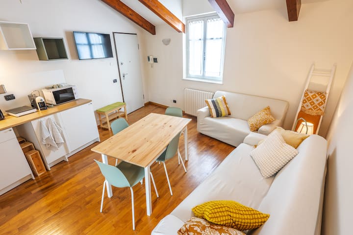 Séjour spacieux avec poutres apparentes, coin repas et canapé-lit confortable. L'environnement est accueillant et bien éclairé, idéal pour se détendre après une journée dans les collines des Langhe ou pour partager un dîner en compagnie.