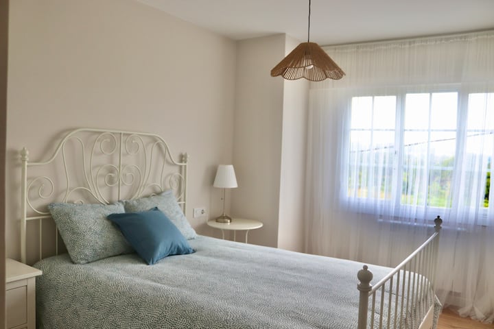 Ოთახი ორადგილიანი საწოლით, ორი მაგიდით და ფართო ჩაშენებული კარადებით.