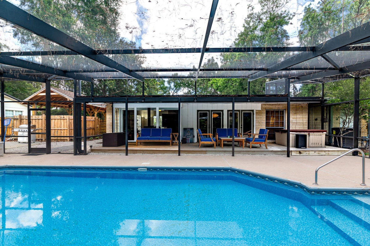 A private screened patio is showcased, featuring a sparkling pool surrounded by a smooth deck. Lounge seating is visible, along with a spa and grill. A spacious indoor area is seen through large sliding glass doors, offering a connection to the outdoor space.