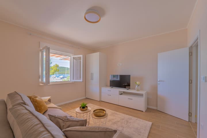 Пространиот дневен простор е посебна соба со врати, со поглед на море. Заштита од мрежа Moschito на прозорците. Има телевизор. Каучот е исто така кауч на спуштање за 2 лица. Вклучена е постелнина. 