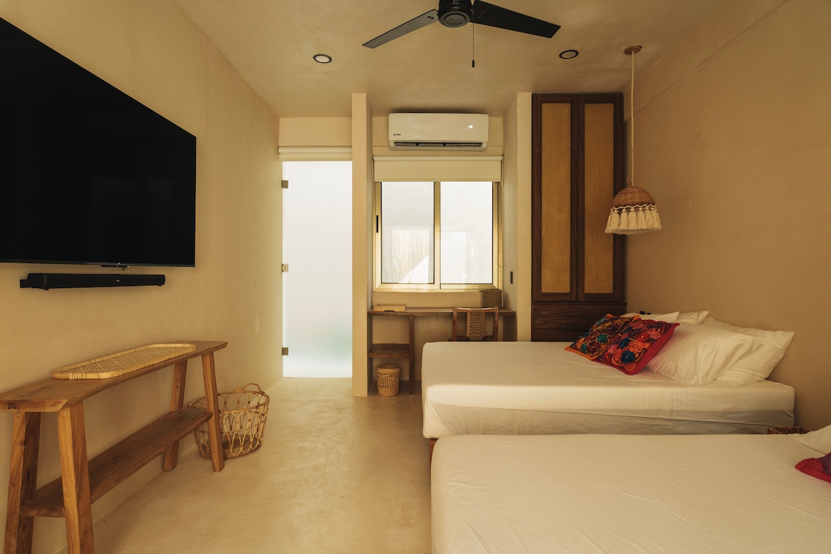 Gastenkamer met twee queensize bedden en een smart-tv.