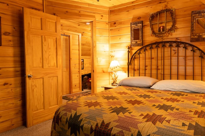 Spálňa 2 v hlavnom zrube na poschodí. Zahŕňa veľký televízor a jednoduchý prístup do kúpeľne na chodbe.