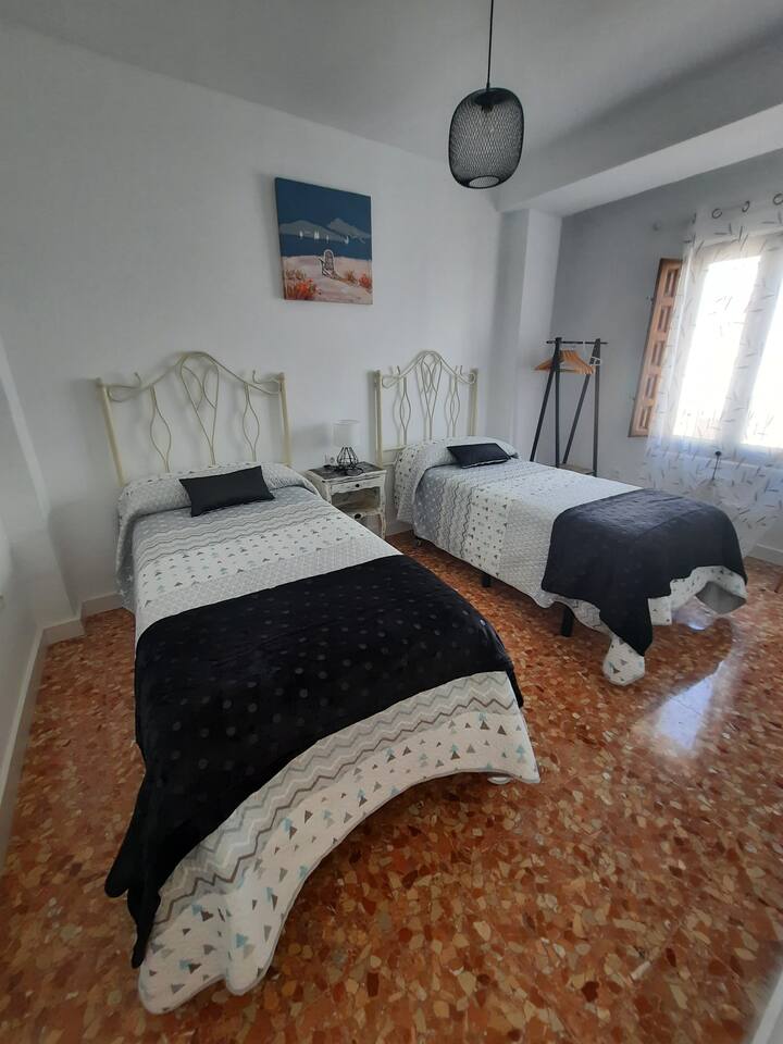 غرفة نوم أرضية مع سريرين فرديين مصنوعين من قبل حرفي محلي، وهي مثالية لإقامة مريحة وأصيلة. نافذة كبيرة مع مصاريع خشبية وأجواء هادئة وديكور رصين مستوحى من الجنوب. مثالية للأصدقاء أو الأطفال.