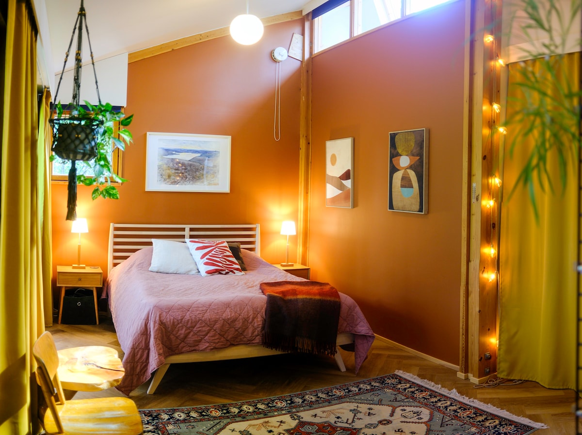 Основната спалня разполага с висок таван и покривни прозорци, които могат да бъдат покрити със светонепропускливи завеси. Удобното двойно легло и топлите тонове са вдъхновени от тухлената и дървена външна част на къщата и теракотените саксии.