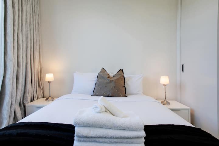 Dit heerlijke queensize bed zorgt ervoor dat je je comfortabel voelt met de frisse witte lakens en gezellige plaid.