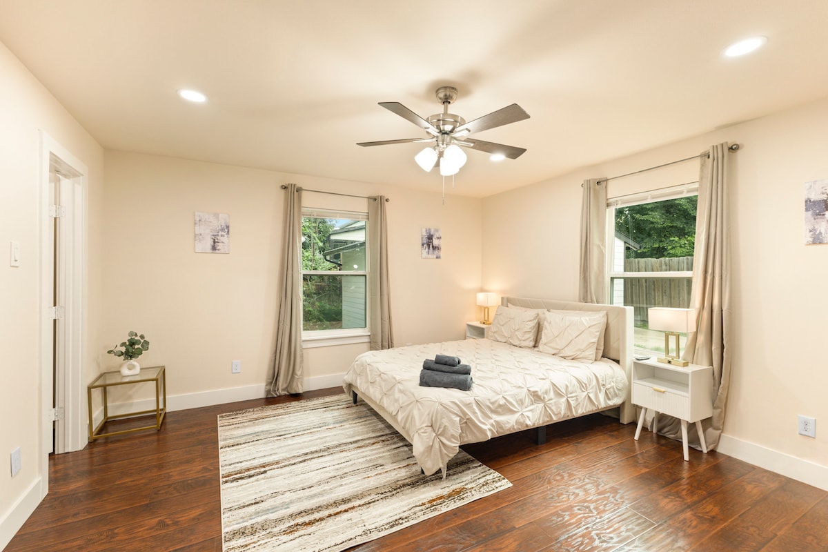 Priestranná hlavná spálňa s manželskou posteľou, elegantným osvetlením a dvojitými oknami pre dostatok prirodzeného svetla. Premyslený dizajn s jemnými tónmi, útulnou posteľnou bielizňou a zatemňovacími závesmi pre pokojný spánok. Zahŕňa stropný ventilátor a nočné stolíky.