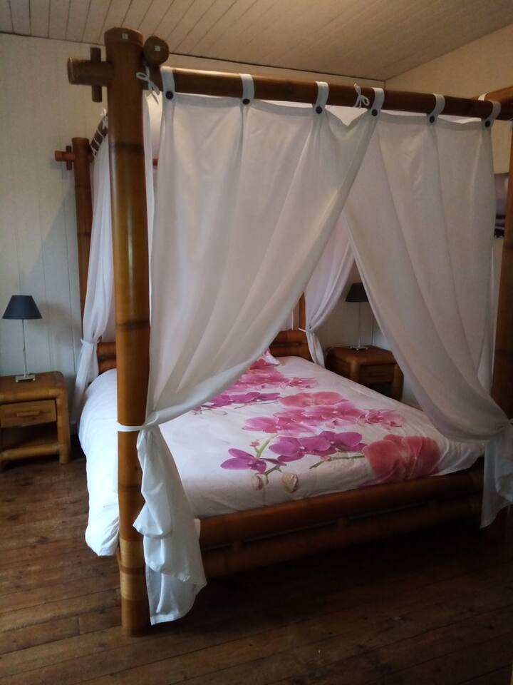 Chambre Passion équipée d'un lit bambou à balqaquin 160x200, une armoire bambou, 2 chevets. Possibilité de rajouter un lit single.