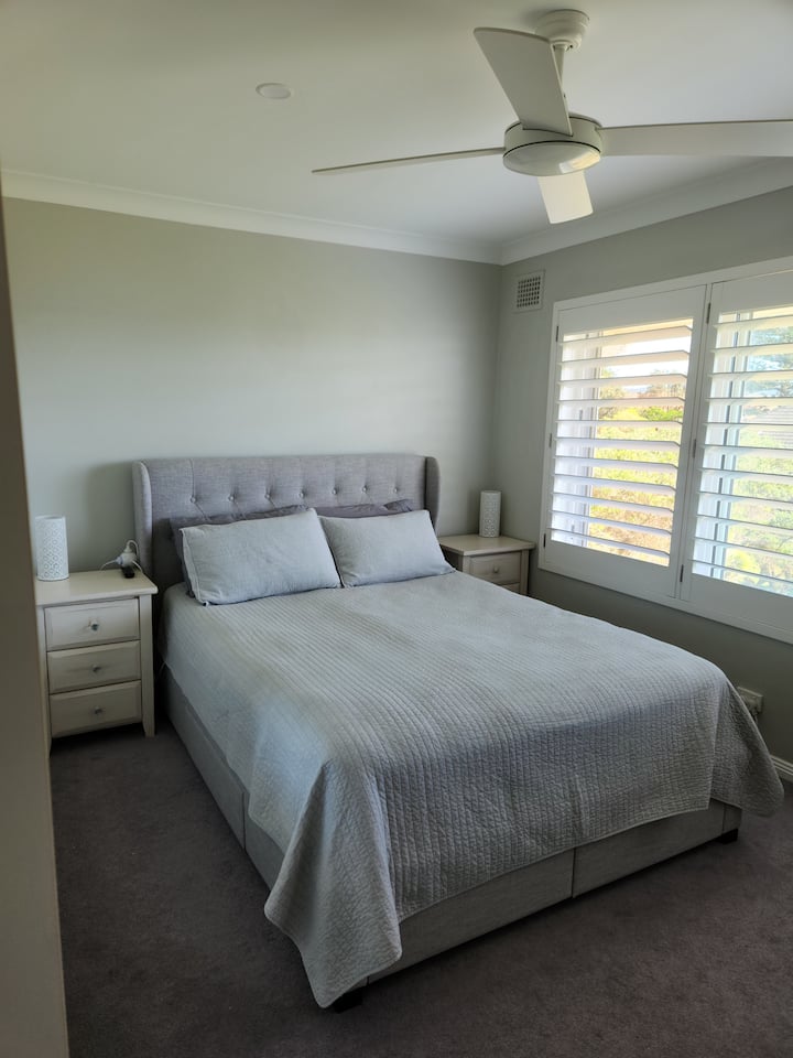 Главна спална соба со брачен кревет (широк 150-179 см), тавански вентилатор, вградена во гардероби и поглед кон изобилство.