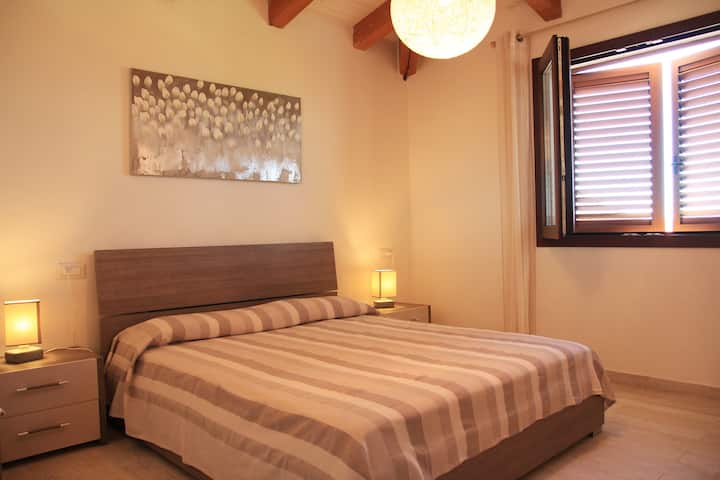 Ფართო საძინებელი კომფორტული ორადგილიანი საწოლით ფანჯრის ჟალუზებიდან მომდინარე რბილ დილის მზის სინათლეზე, რომელიც შეგიძლიათ გადაწყვიტოთ, ღიად დატოვებთ თუ დახურულს.