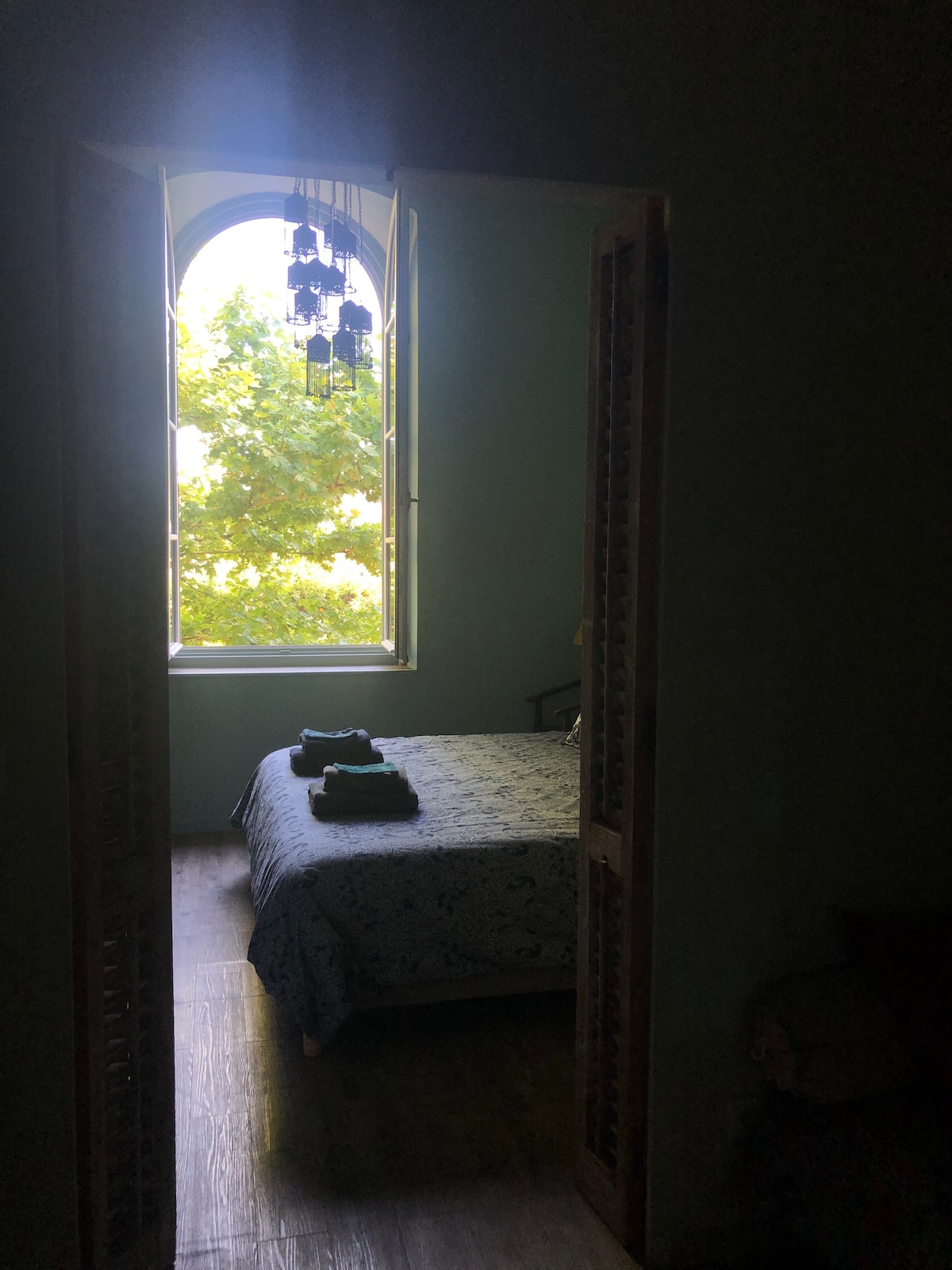 Modrozelená spálňa a jej ogive okno na rovinatých stromoch parku