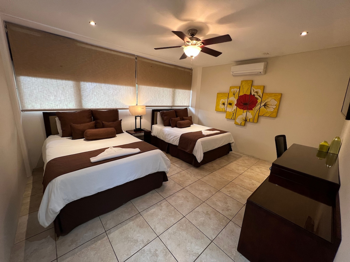 Bedroom with 2 queen beds and a desk. 