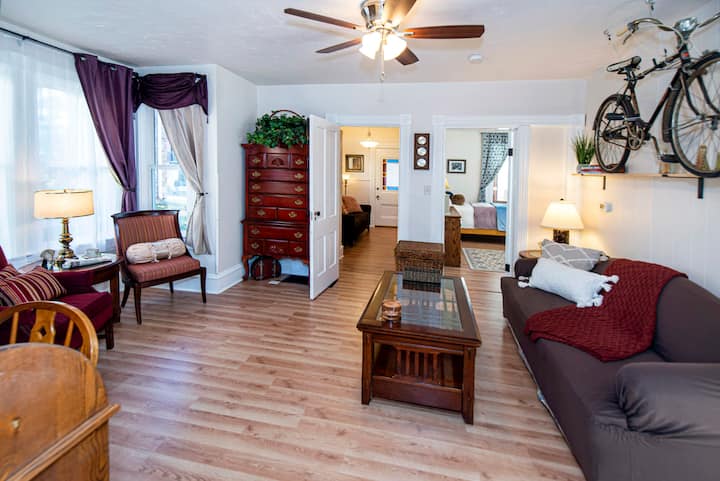 Spacious living room with ceiling fan.  There is also a large dresser for clothes storage. Queen size sofa bed with pillows and bedding.