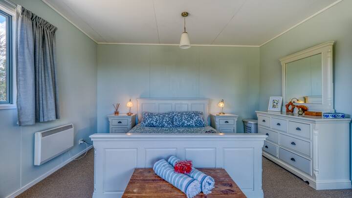 מיטת קווין סייז נוחה בחדר השינה המרווח עם שידה וארון מצעים מאפשרים לכם להתמקם עם מקום לזוז.