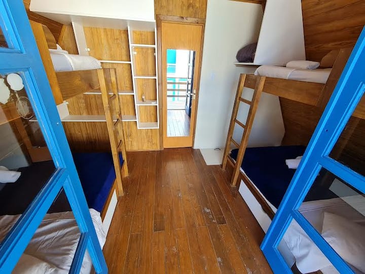 Chatka s dvoma poschodovými posteľami,  dvoma oddelenými posteľami  a dvoma manželskými posteľami. Zrkadlo pri dverách, ktoré prechádzajú cez apartmán.