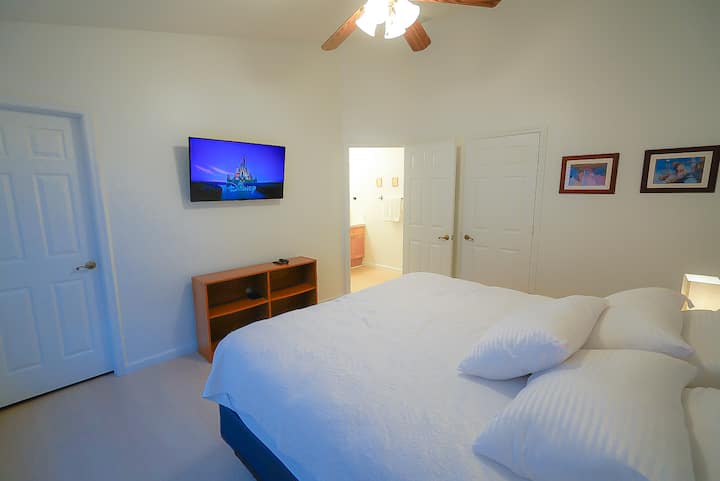 Master bedroom featuring a smart TV, wireless chargers in each nightstand, a walk-in closet and a private bathroom.