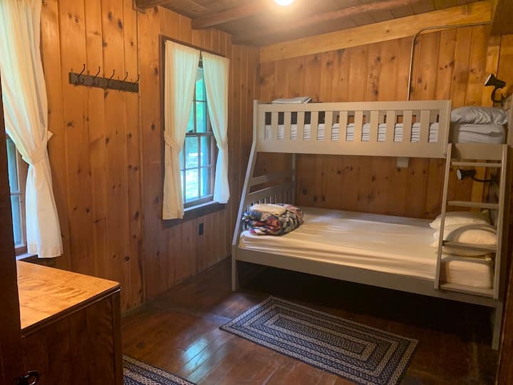 La chambre deux dispose d'un lit superposé avec matelas double en bas et de lits jumeaux au-dessus.  Chaque lit superposé dispose d'une lampe de lecture et la chambre dispose également d'une commode et d'un banc.
