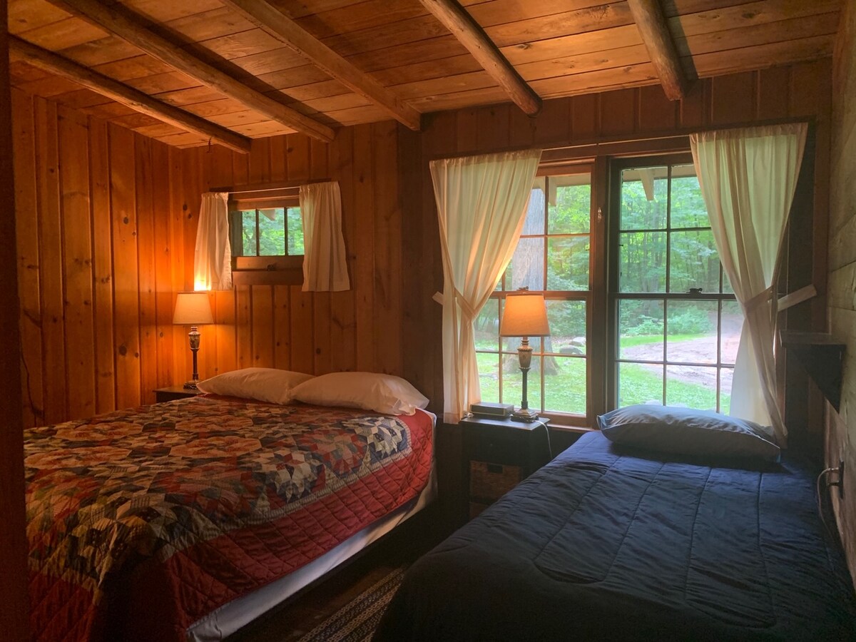 Bedroom one has a double bed and twin bed with night stands, table lamps and a bench. 