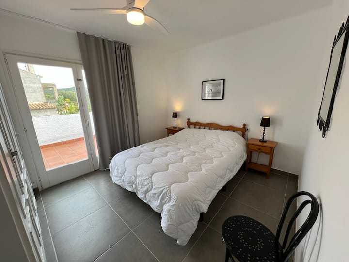 Au premier étage, chambre avec terrasse, lit double et placard. Il y a un ventilateur de plafond. 