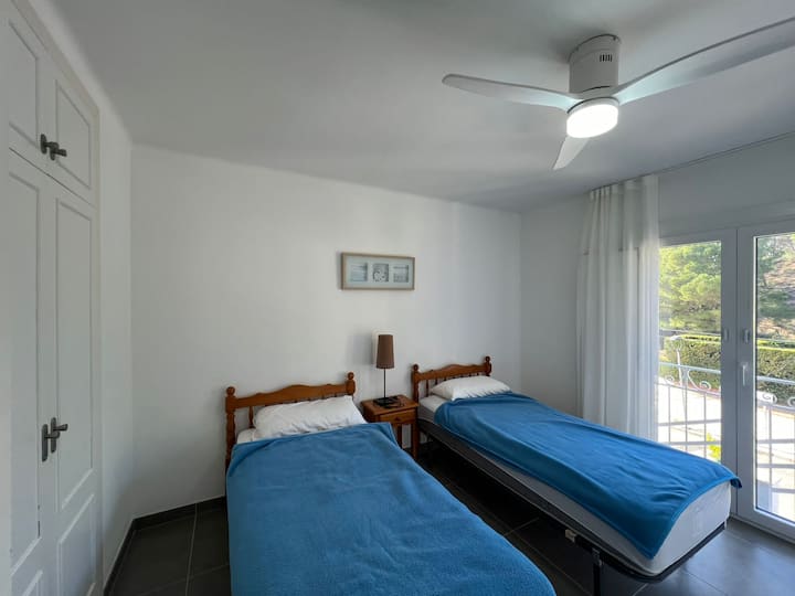 Chambre au premier étage avec 2 lits simples et placard. Il y a un ventilateur de plafond. Vue sur la rue et la forêt. 