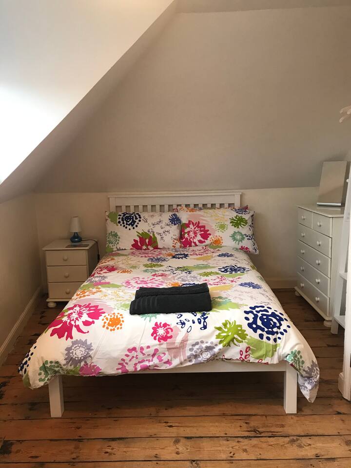 Dormitorio doble en el segundo piso con una cama doble pequeña e individual.