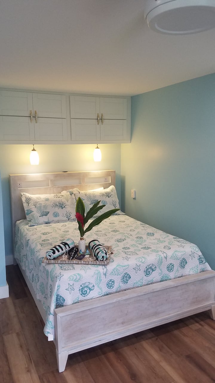 Cama tamaño queen con iluminación junto a la cama