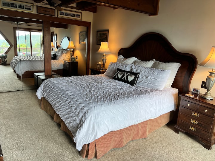 Krevat me përmasa mbretërore me dollapë të pasqyruar që pasqyrojnë dritaret dhe pamjen