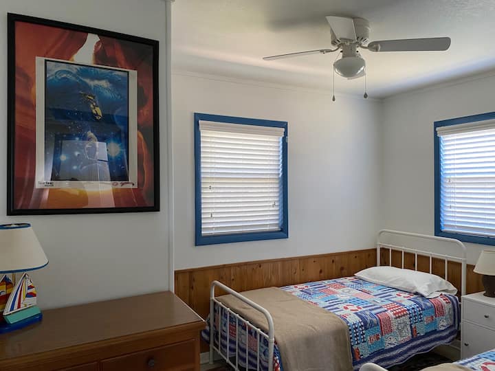 เตียงแฝดตู้เสื้อผ้าตู้เสื้อผ้าและพัดลมเพดาน  โต๊ะข้างเตียงมีพอร์ตชาร์จ USB 2 พอร์ตและปลั๊กไฟรวมถึงพอร์ตชาร์จ USB 2 พอร์ตที่เต้าเสียบติดผนังไฟฟ้า