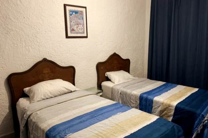Air-conditioned room with two single beds.