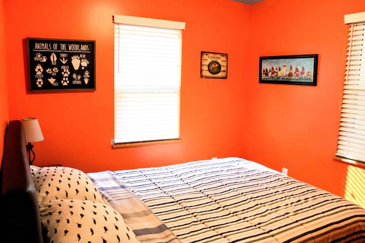 The Orange Room- Queen Bed. Downstairs bedroom with chest of drawers, nightstands, and lamps. This bedroom is located separately from the other downstairs bedrooms, affording it additional privacy.