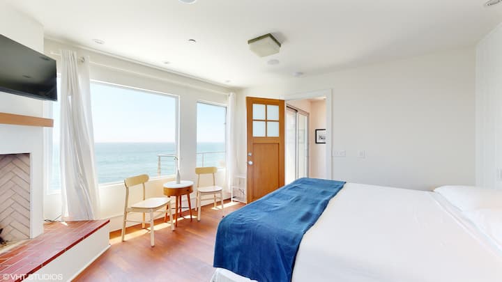 宽敞的卧室，可欣赏海景、电视、附属办公室、套内浴室和步入式衣橱。
