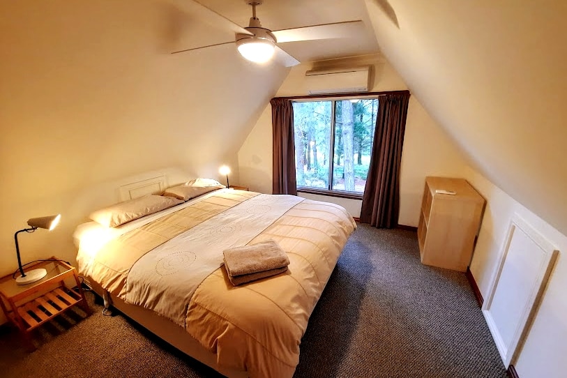 The third bedroom includes a queen bed fitted with an electric blanket, reverse-cycle air conditioner, ceiling fan, mirror and storage shelf unit