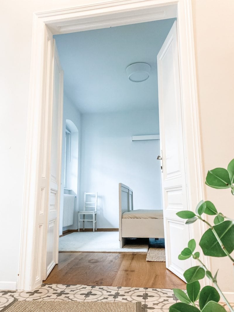 A view from the foyer into the guest bedroom, which features two single beds and views into the private garden. Each room has double-paned windows, a screen for bug-free breezes, and room-darkening blinds. 