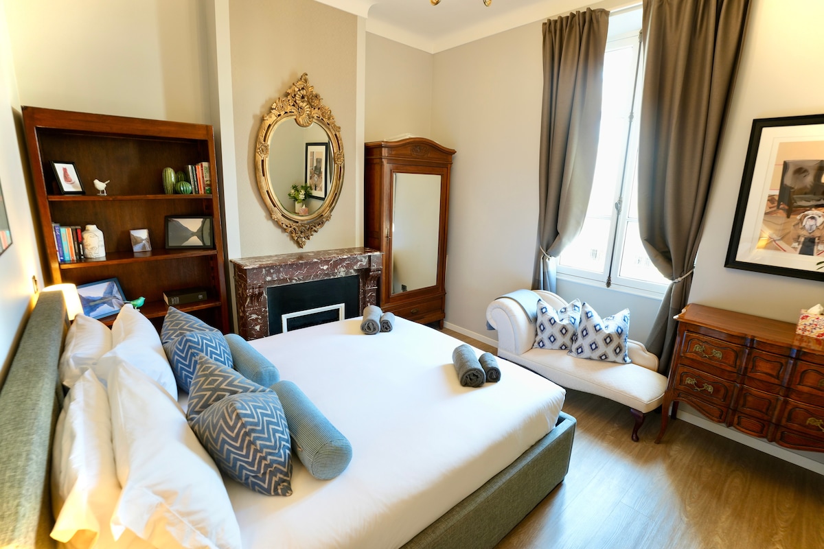 Dormitorio principal con cama tamaño king, ropa de cama de lujo y muebles antiguos. 