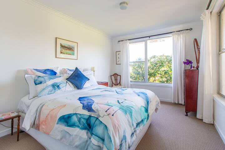 A comfortable queen-sized bedroom with designer linen and views of the garden