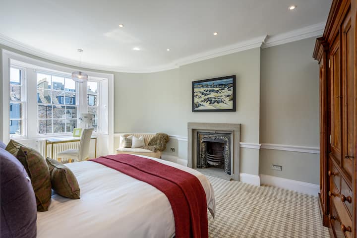 חדר שינה ראשי עם מיטת קינג סייז, אח מקורית, מאפיינים תקופתיים ונופים מאחור