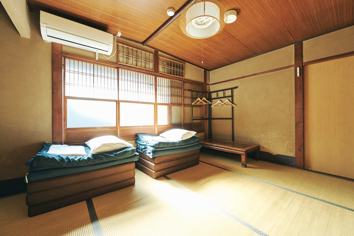 築100年の元料理旅館を用いたゲストハウス。客室は2階にあります。京都の伝統的な木造の建物で、畳に布団を敷いて寝る宿泊をお楽しみください。
Japanese-style beds in an antique room
