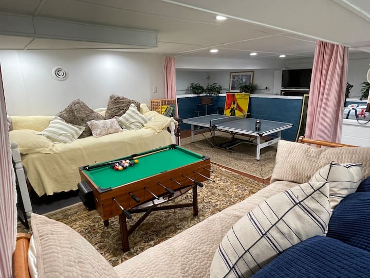 Basement with daybeds for sleeping, ping pong, and a bathroom.