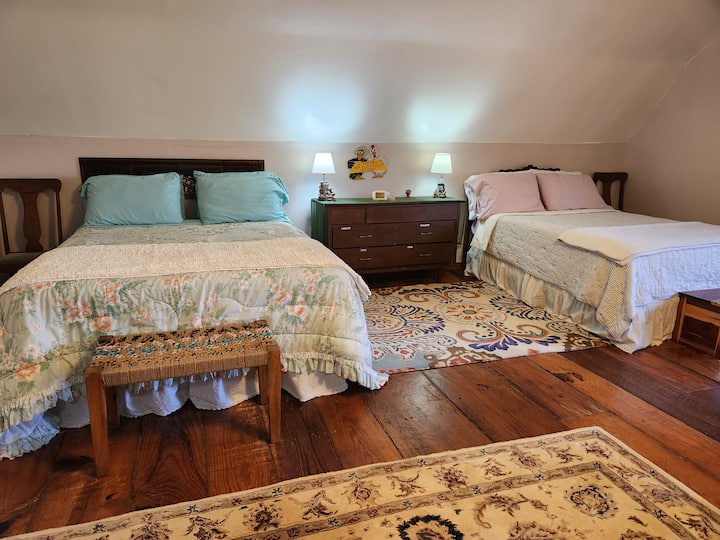 บริเวณห้องนอนพร้อมเตียงควีนไซส์และเตียงขนาดเต็มในห้องใต้หลังคาชั้นบน