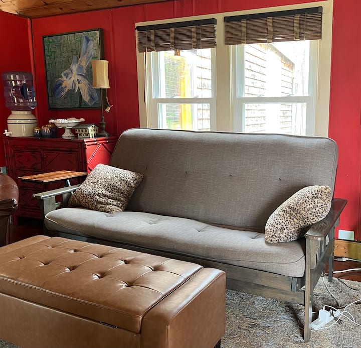 客厅舒适的日式床垫沙发，配有脚凳和窗户，可俯瞰后院和花园