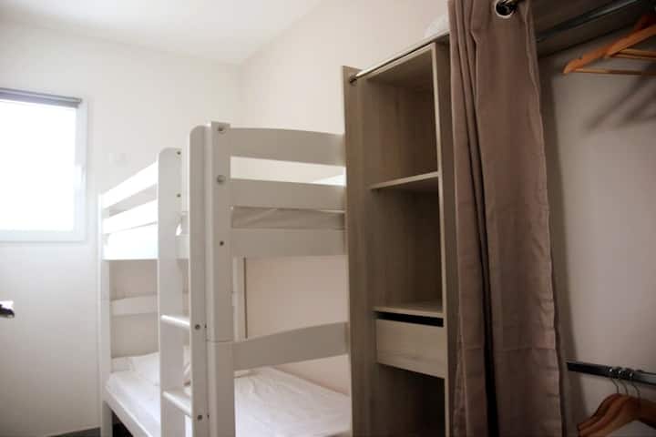 חדר הילדים הקטן עם שתי מיטות יחיד 80x190 ס"מ, מלתחה לעסקים וחלון המשקיף על המרפסת הפרטית.