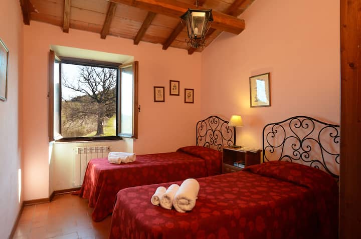 De tweede kamer, langs de gang, is een tweepersoonskamer uitgerust met een kast en een centraal nachtkastje met drie praktische laden, ideaal voor het bieden van ruimte en comfort tijdens je verblijf.