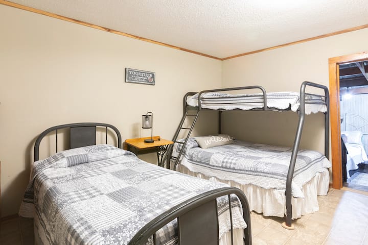 Full size bed on bottom bunk and single on top with another twin bed.